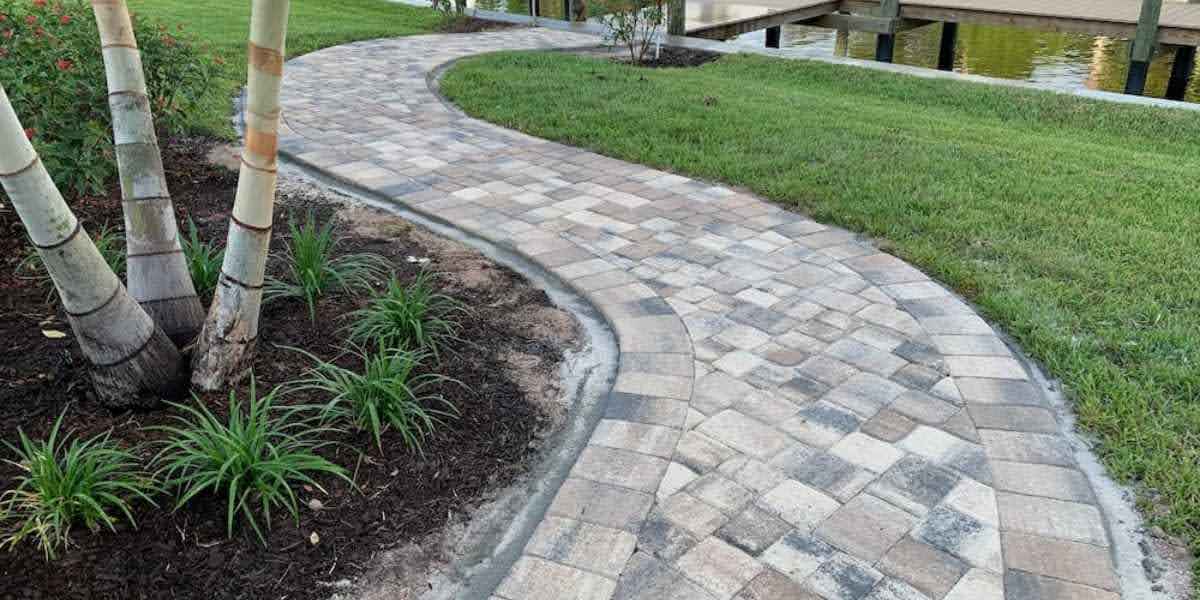 how-to-seal-pavers-in-florida A newly sealed paver walkway in Florida with a smooth, curved design leading to a dock, demonstrating the results of proper paver sealing. This image supports a guide on how to seal pavers in Florida for durability and protection.