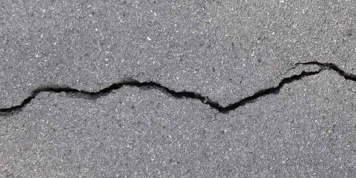 Close-up of cracked asphalt surface showing signs it’s time to repave driveway due to structural damage and surface deterioration.