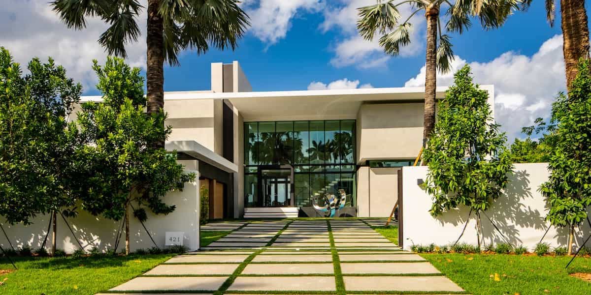 Modern home with large-format slab paver driveway and grass strips under palm trees, illustrating luxury driveway ideas.
