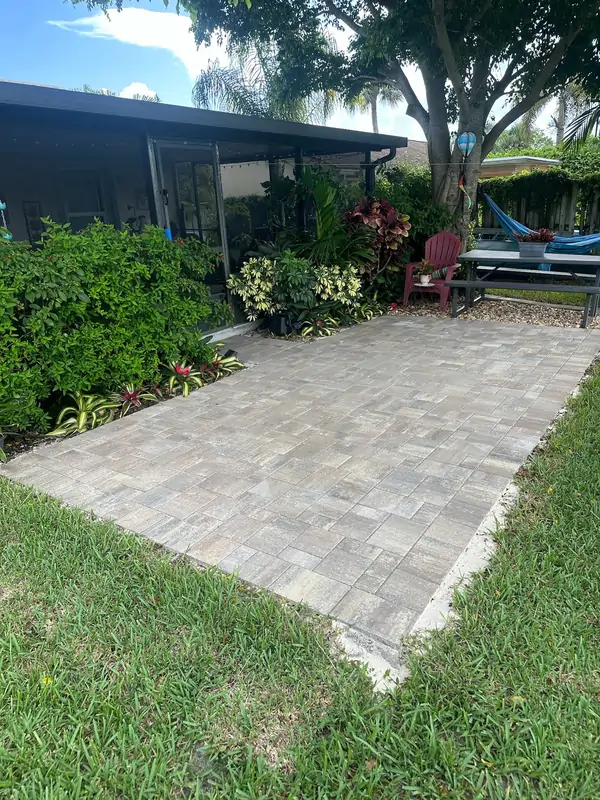 Residential backyard patio with gray concrete pavers installed near landscaping and outdoor seating area