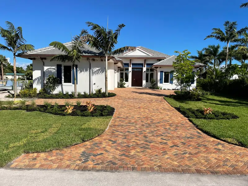 Curved brick paver driveway installation leading to luxury Florida home with tropical landscaping