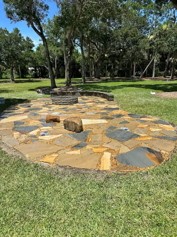 Natural flagstone patio installation with stone fire pit seating area in backyard landscape
